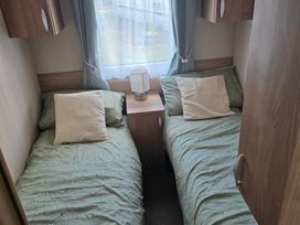 A bedroom with two single beds and a lamp at Ty Gwyn Caravan Park - Holiday Accommodation 22189 Abergele