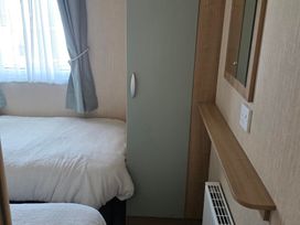 A bedroom with two beds and a wardrobe at Ty Gwyn Caravan Park - Holiday Accommodation 22189 Abergele