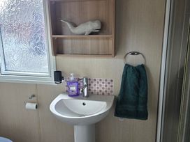 A bathroom featuring a sink, tap, towel, and shelf at Ty Gwyn Caravan Park - Holiday Accommodation 22189 Abergele