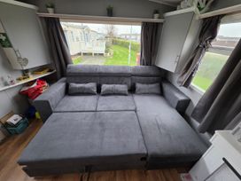 A living room with a sofa and pillows at Kingfisher Caravan Park - Holiday Accommodation 22193 in Ingomells