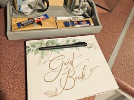 A guest book with a pen and coffee sachets on a tray at Kingfisher Caravan Park - Holiday Accommodation 22193 in Ingomells