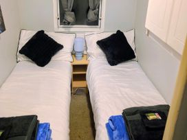 A bedroom with two single beds and a lamp at Kingfisher Caravan Park - Holiday Accommodation 22193, Ingomells
