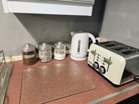A kitchen countertop with a kettle, toaster, and jars for coffee, tea, and sugar at Kingfisher Caravan Park - Holiday Accommodation 22193 Ingomells