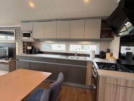 A kitchen with cabinets, sink, and appliances at Hafan y Mor Haven - Holiday Accommodation 22224 Pwllheli