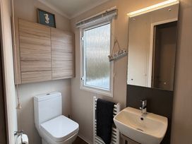 A bathroom with a sink, toilet, and mirror at Hafan y Mor Haven - Holiday Accommodation 22224 Pwllheli