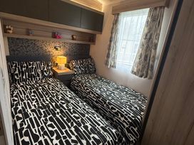 A bedroom with two single beds and a bedside lamp at Hafan y Mor Haven - Holiday Accommodation 22224, Pwllheli