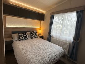 A bedroom with a bed, bedside table, and window at Hafan y Mor Haven - Holiday Accommodation 22224, Pwllheli
