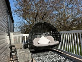A hanging chair and outdoor chair on a decking area at Hafan y Mor Haven - Holiday Accommodation 22224 Pwllheli