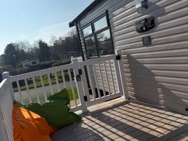 A deck area with a gate and colorful cushions at Hafan y Mor Haven - Holiday Accommodation 22224 Pwllheli