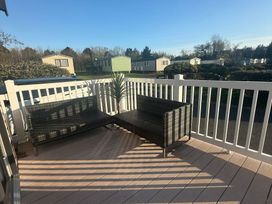 A balcony with rattan furniture and a potted plant at Hafan y Mor Haven - Holiday Accommodation 22224 Pwllheli