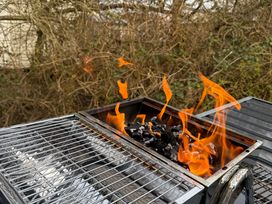 A grill with flames and charcoal outdoors at Hafan y Mor Haven - Holiday Accommodation 22224, Pwllheli