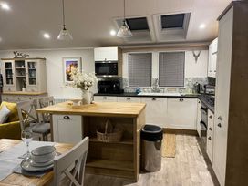 A kitchen with cabinets, appliances and a dining area at White Acres Holiday Park - Holiday Accommodation 22327, Whitecross, Newquay