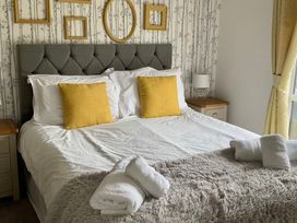 A bedroom featuring a bed with yellow pillows and a bedside table at White Acres Holiday Park - Holiday Accommodation 22327, Whitecross, Newquay