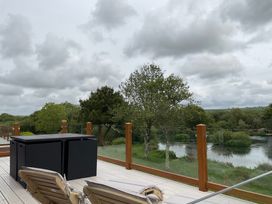 A deck area with outdoor furniture overlooking a body of water at White Acres Holiday Park - Holiday Accommodation 22327, Whitecross, Newquay