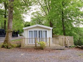 A cabin with decking surrounded by trees at 145 Woodside View in Porthmadog