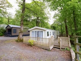 A mobile home with a deck and trees at 145 Woodside View in Porthmadog