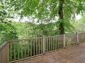 A wooden deck area surrounded by trees at 145 Woodside View in Porthmadog