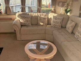 a corner sofa with decorative cushions and a coffee table at Coral Beach - Holiday Accommodation 22375 in Ingoldmells