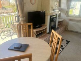 a living room with a table and chairs, a television, and a fireplace at Coral Beach - Holiday Accommodation 22375 in Ingoldmells