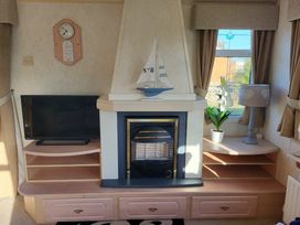 a living room with a fireplace, a television, and shelves at Coral Beach - Holiday Accommodation 22375 in Ingoldmells