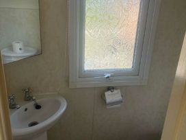 a small bathroom with a sink, mirror, and window at Coral Beach - Holiday Accommodation 22375 in Ingoldmells