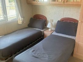 a bedroom with two single beds and a bedside lamp at Coral Beach - Holiday Accommodation 22375 in Ingoldmells