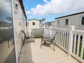 An outdoor area with chairs on a decking at Ty Mawr Holiday Park - Holiday Accommodation 22393, Towyn
