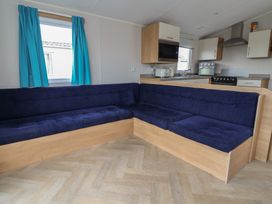 A living room with a corner sofa and kitchen unit at Ty Mawr Holiday Park - Holiday Accommodation 22393, Towyn