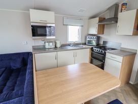 A kitchen with appliances and a table at Ty Mawr Holiday Park - Holiday Accommodation 22393 Towyn