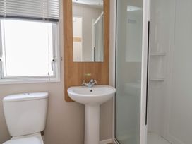 A bathroom with a toilet, sink, mirror, and shower at Ty Mawr Holiday Park - Holiday Accommodation 22393 in Towyn