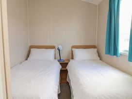 A bedroom with two single beds and a lamp at Ty Mawr Holiday Park - Holiday Accommodation 22393 in Towyn