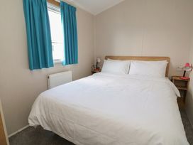 A bedroom with a double bed and curtains at Ty Mawr Holiday Park - Holiday Accommodation 22393 in Towyn