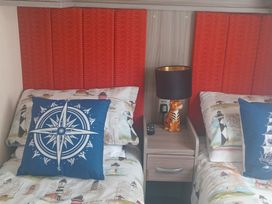 A bedroom with two beds and a lamp at Primrose Valley Holiday Park - Holiday Accommodation 2533, Filey