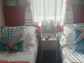 A bedroom with two single beds and a bedside table at Primrose Valley Holiday Park - Holiday Accommodation 2533 Filey