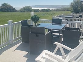 A terrace with chairs and a table overlooking a lawn at Primrose Valley Holiday Park - Holiday Accommodation 2533, Filey