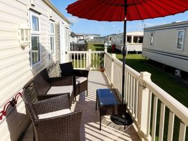 An outdoor area with chairs and an umbrella at Coastfield Holiday Village - Holiday Accommodation 2604 in Ingoldmells