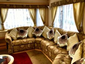 A living room with a large sofa and cushions at Coastfield Holiday Village - Holiday Accommodation 2604 in Ingoldmells