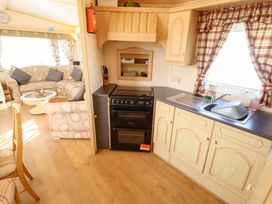 A living room with sofa and kitchen area at Coastfield Holiday Village - Holiday Accommodation 2604 in Ingoldmells