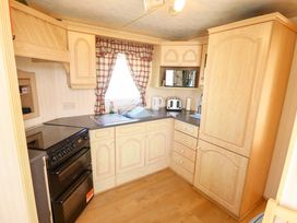 A kitchen with cabinets, sink, oven and appliances at Coastfield Holiday Village - Holiday Accommodation 2604 in Ingoldmells