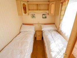 A bedroom with two beds and a bedside table at Coastfield Holiday Village - Holiday Accommodation 2604 in Ingoldmells