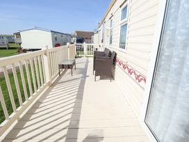A deck with chairs and a table at Coastfield Holiday Village - Holiday Accommodation 2604 Ingoldmells