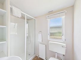 A bathroom featuring a shower, toilet, radiator, and window at St Andrews Holiday Park - Holiday Accommodation 2944 in St Andrews