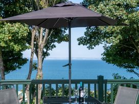 An outdoor space with a table and umbrella overlooking the ocean at St Andrews Holiday Park - Holiday Accommodation 2944 St Andrews
