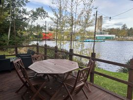 A deck with a table and chairs overlooking a body of water at Haggerston Castle - Holiday Accommodation 3441, Berwick-upon-Tweed