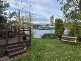 An outdoor area with a patio, table, and chairs near a lake at Haggerston Castle - Holiday Accommodation 3441, Berwick-upon-Tweed
