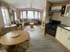 A living room with a sofa and dining table at Happy Days Caravan Park - Holiday Accommodation 3599 Towyn