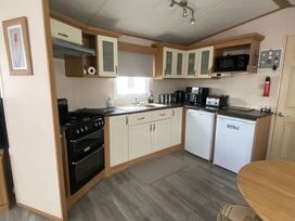 A kitchen with stove, sink, and appliances at Happy Days Caravan Park - Holiday Accommodation 3599 Towyn