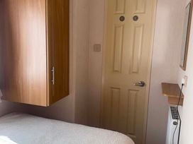 A bedroom with a cabinet and door at Happy Days Caravan Park - Holiday Accommodation 3599 Towyn
