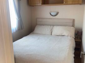 A bedroom with a bed and a lamp at Happy Days Caravan Park - Holiday Accommodation 3599, Towyn