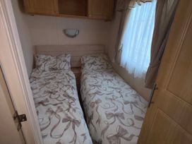 A bedroom with two single beds and a mirror at Happy Days Caravan Park - Holiday Accommodation 3599 Towyn